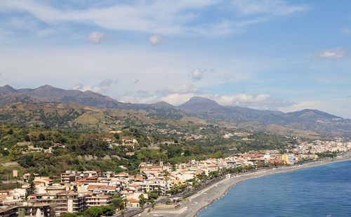 Seaside, town by the sea, gray sand, beaches and road along, coast around taormina, sicily	
