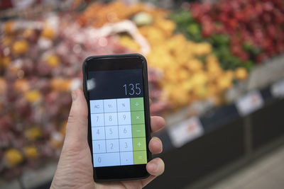 Hand holding calculator in supermarket