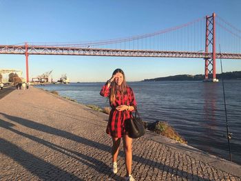 Full length portrait of woman standing against golden gate bridge