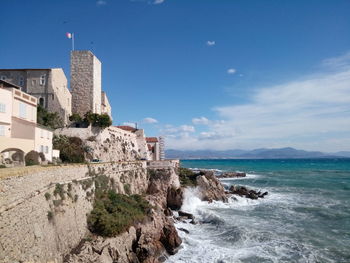 Scenic view of sea by buildings against sky