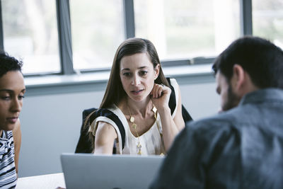 Businesswoman explaining to colleagues in meeting at office