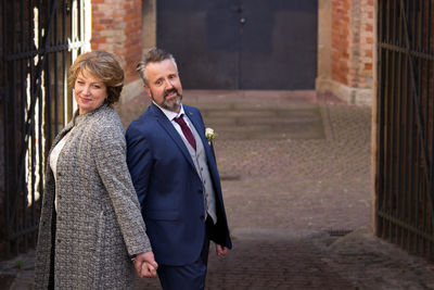 Mature couple holding hands while standing on footpath