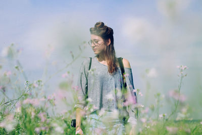 Young woman in meadow against sky