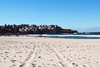 View of beach of coastal town against clear blue sky