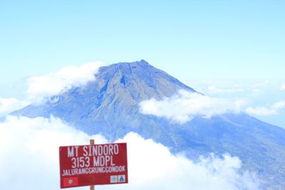 Information sign on snowcapped mountain against sky