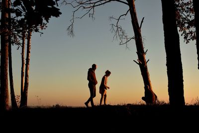 Silhouette people on field against sky during sunset