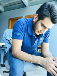 Young man looking away while sitting on table