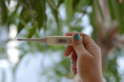Close-up of woman hand holding thermometer