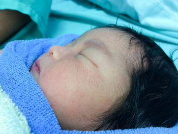 Close-up of newborn baby sleeping on hospital bed