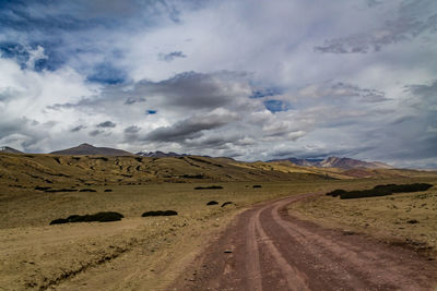 Scenic view of dirt road against sky