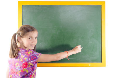 Portrait of girl writing on green board in classroom