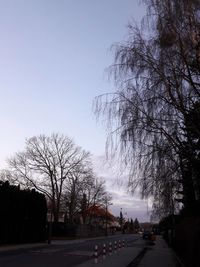 Road amidst bare trees against clear sky