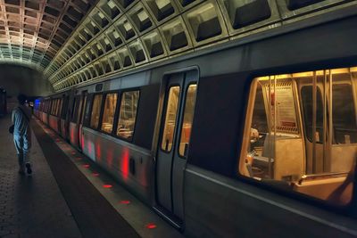 Rear view of woman walking on subway platform by train