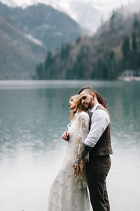 A happy couple in love and married embrace in nature by the lake and the misty mountains