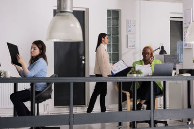 Rear view of woman using digital tablet in office