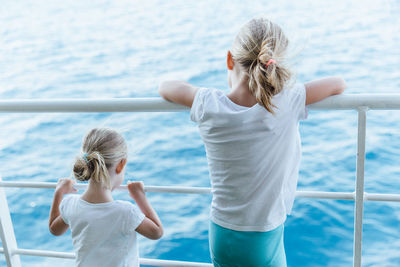 Rear view of girl with arms raised against sea