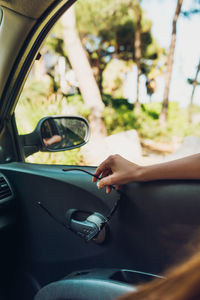 Cropped hand of person holding sunglasses by window in car