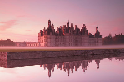 Reflection of buildings in lake during sunset