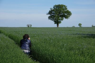 Rear view of man on field against sky