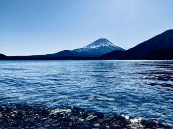 Scenic view of sea and mountains against clear blue sky