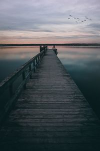 Pier over sea against sky during sunset