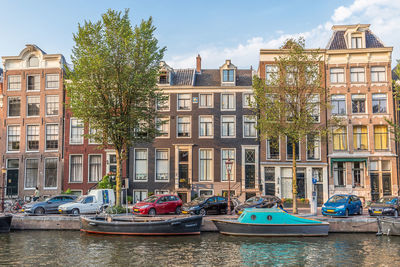 Sailboats moored on canal by buildings in city