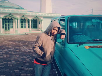 Portrait of man standing by vehicle