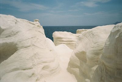 Rock formations on beach against sky