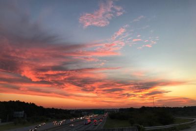 Cars on road against sky during sunset