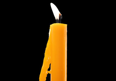 Close-up of yellow candle against black background