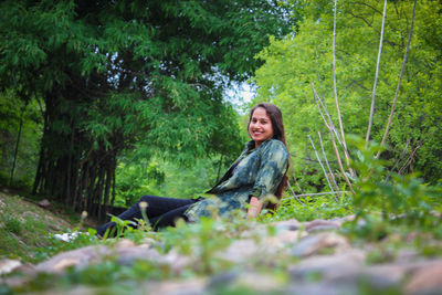 Portrait of smiling young woman sitting on land