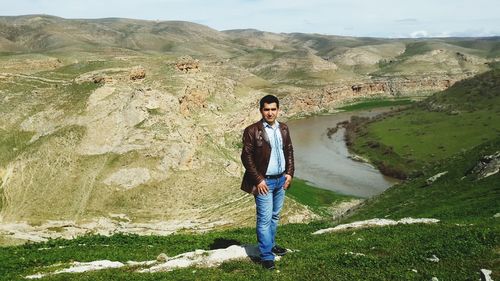 Full length portrait of mature man standing against landscape