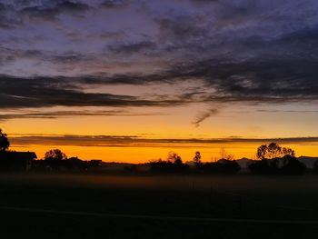 Scenic view of silhouette field against sky during sunset