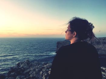 Rear view of woman looking at horizon during sunset