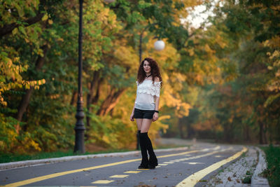 Full length of woman standing on road amidst trees