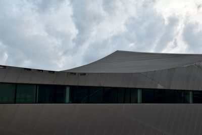 Low angle view of modern building against cloudy sky