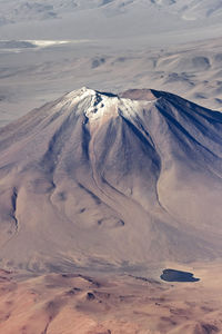 Aerial photography of the andes, brown landscape and desert with a volcano and a lagoon