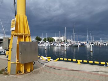 Sailboats in harbor by sea against sky