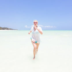 Beautiful woman running on beach against sky