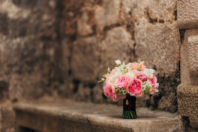 Woman with pink flower against wall