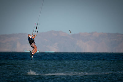 Man kiteboarding over sea against sky