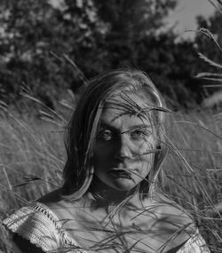 Portrait of young woman standing against plants on field