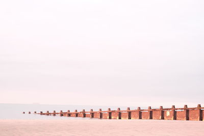 Wooden posts on beach against clear sky