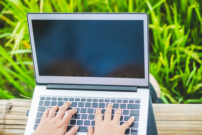 Low section of woman using laptop while sitting outdoors