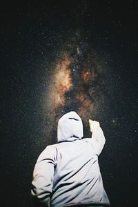 Rear view of man standing against star field at night