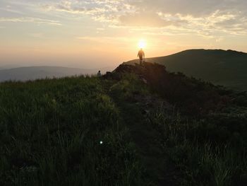 Silhouette man hiking on mountain against sky during sunset