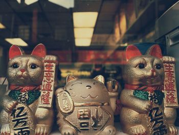 Maneki nekos seen through glass at store for sale