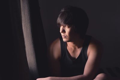 Portrait of young woman looking away while sitting in darkroom