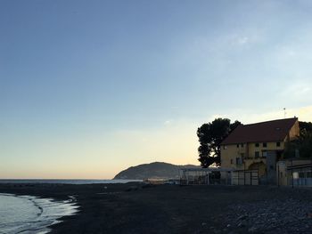 Houses by sea against sky during sunset