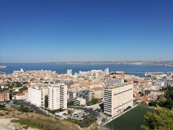 High angle view of cityscape by sea against clear sky